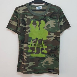 May include: Green camouflage t-shirt with a green graphic of a tree with the word "POLLUTION" printed below it.