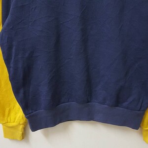 May include: A blue and yellow long-sleeved sweatshirt with a ribbed hem.