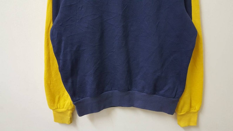 May include: A blue and yellow long-sleeved sweatshirt with a ribbed hem.