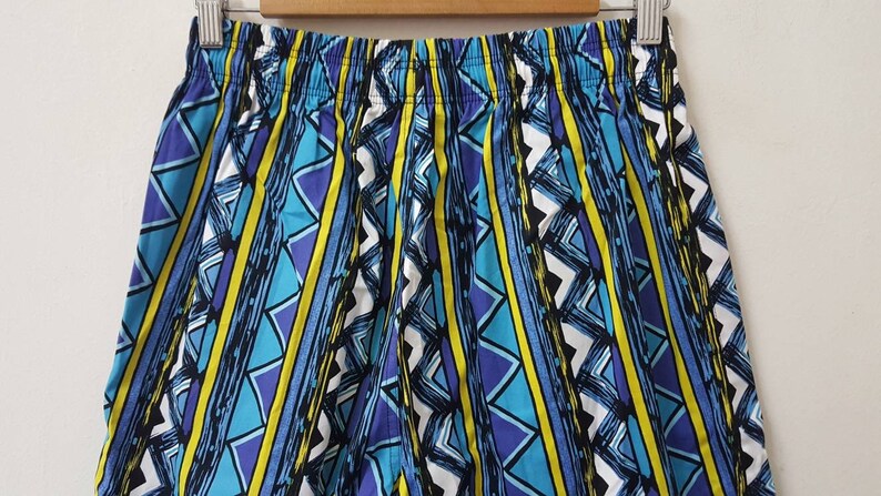 May include: Blue, yellow, and purple patterned shorts with a geometric design.