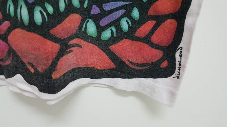 Puede incluir: Primer plano de una tela negra y blanca con un dise&ntilde;o abstracto colorido. La tela tiene un borde blanco y la firma "Nicholson" es visible en la esquina inferior derecha.