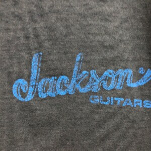 May include: A blue and white logo on a dark gray background that reads "Jackson Guitars".