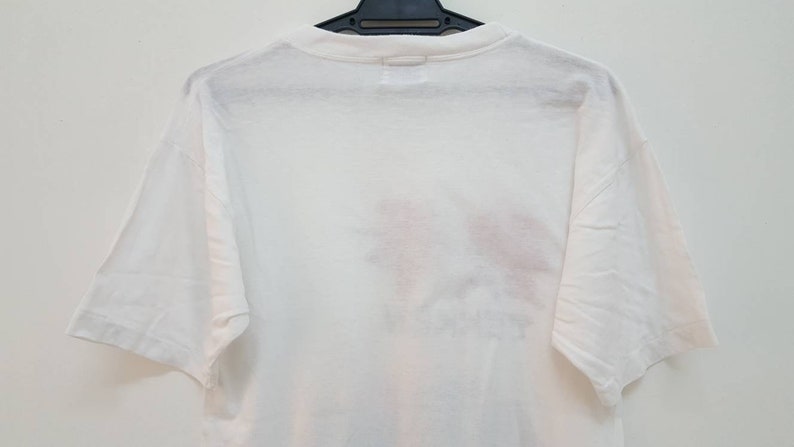 May include: White short-sleeved t-shirt with a faded graphic print on the back.