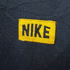 May include: A yellow fabric patch with black stitching and the word "NIKE" in black lettering.