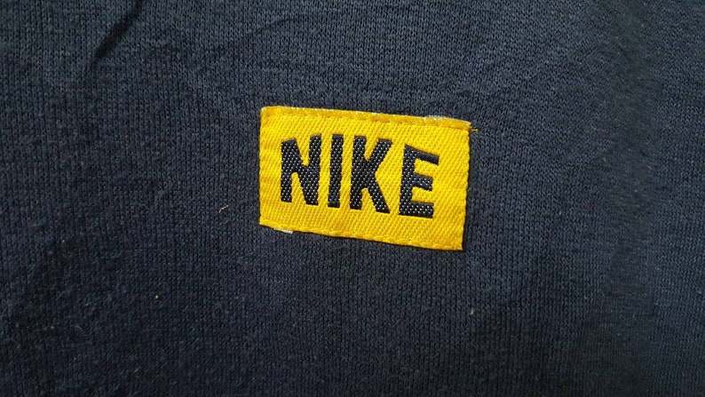 May include: A yellow fabric patch with black stitching and the word "NIKE" in black lettering.