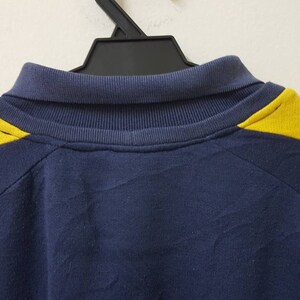 May include: A navy blue sweatshirt with yellow accents on the shoulders. The sweatshirt has a mock neck collar.