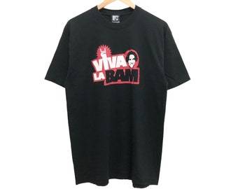 Könnte beinhalten: Schwarzes T-Shirt mit dem Schriftzug "VIVA LA BAM" in Rot und Weiß, zusammen mit einer Grafik eines Gesichts und einer Rock'n'Roll-Handgeste. Das T-Shirt hängt an einem Holzkleiderbügel.