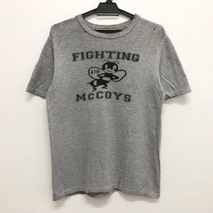 May include: Gray short-sleeved t-shirt with a black graphic of a bee and the text "FIGHTING MCCOYS".