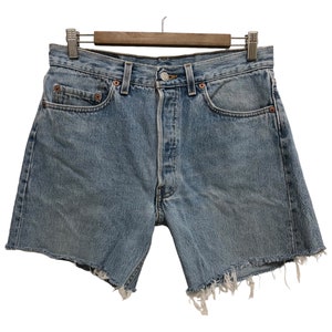 May include: Light blue denim shorts with a frayed hem. The shorts have a button fly and five pockets.