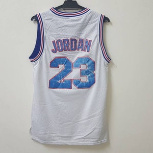 May include: White basketball jersey with blue and red trim. The back of the jersey has the name "JORDAN" and the number "23" in blue with a white outline.