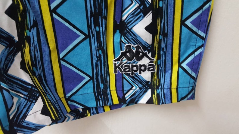 May include: Blue, yellow, and white patterned swim trunks with a black Kappa logo.