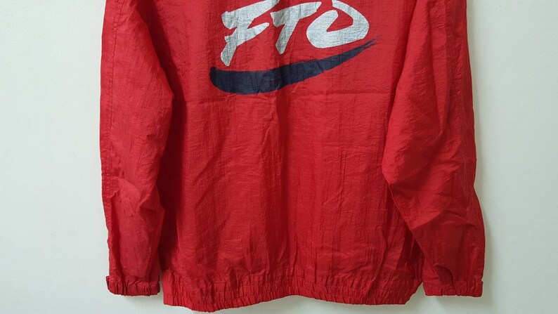 May include: Red windbreaker jacket with a white and blue logo that says "FTO" in a stylized font.
