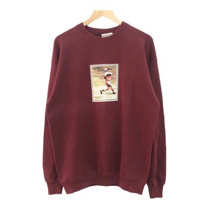 May include: A maroon sweatshirt with a vintage baseball player graphic on the front. The graphic is a photo of a baseball player in action, with the text "Twenty Five" above him.