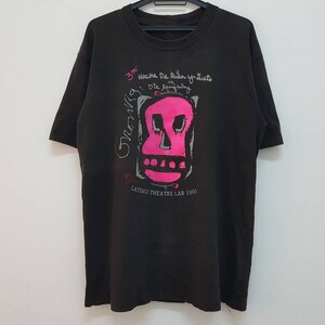 May include: Black t-shirt featuring a pink skull graphic and the text "3er Noche De Risa y Tributos a la Jaula" and "LATINO THEATRE LAB 1991".
