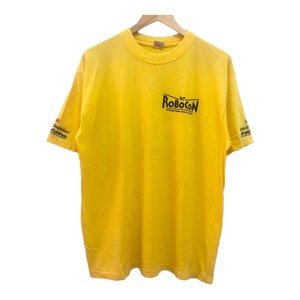 Puede incluir: Camiseta amarilla de manga corta con el texto "97 Robocon International Robocon" impreso en la parte delantera.
