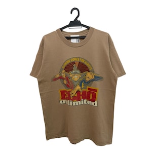 Puede incluir: Camiseta color canela con un gráfico que presenta tres figuras de dibujos animados y el texto "WARNING DOMES FOR ALWAYS" y "ECHO unlimited" en rojo y blanco. La camiseta está colgada de una percha negra.