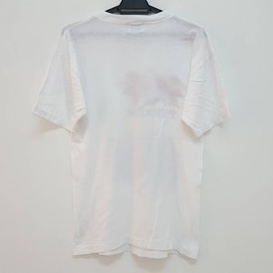 May include: White short-sleeved t-shirt with a faded graphic print on the back.