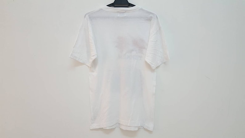 May include: White short-sleeved t-shirt with a faded graphic print on the back.