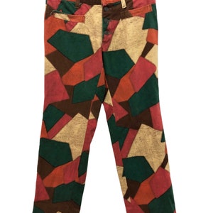 May include: A pair of trousers with a patchwork design in shades of brown, green, orange, and pink. The trousers have a button fly and are made of a soft, comfortable fabric.