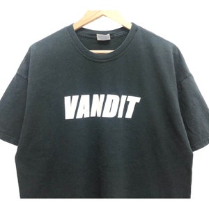 May include: A dark green t-shirt with the word "VANDIT" printed in white on the front.