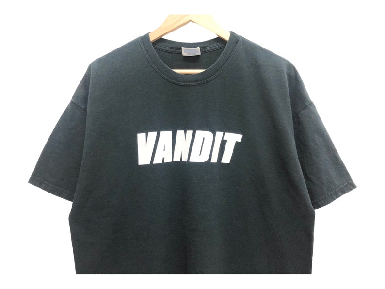 May include: A dark green t-shirt with the word "VANDIT" printed in white on the front.
