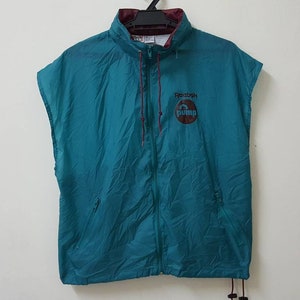 May include: Teal sleeveless jacket with a zipper closure and a Reebok Pump logo on the front.