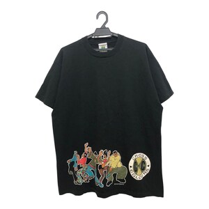 May include: Black t-shirt with a graphic of dancing figures in various colours. The shirt has a crew neck and short sleeves. A circular logo with the text "CROSS COLOURS" is on the lower right. The t-shirt is hanging on a black hanger.