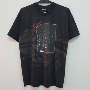 Peut inclure: T-shirt noir avec un imprimé délavé d'un groupe appelé "The Cure" et une photo d'une foule de personnes. Le nom du groupe est en rouge.