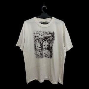 May include: A short-sleeved, off-white crew neck t-shirt featuring a black ink-style graphic print on the chest. The illustration depicts two anthropomorphic dog characters in a comic strip layout, with two smaller panels above a larger central image.