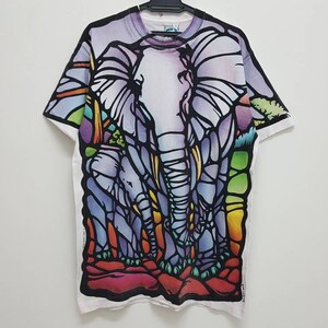 Puede incluir: Camiseta blanca con un dise&ntilde;o de elefantes en vitral de colores. Los elefanten son morados, azules, verdes, amarillos y naranjas.