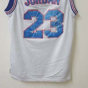May include: White basketball jersey with blue and red trim. The back of the jersey has the number 23 in blue with a water-like design.