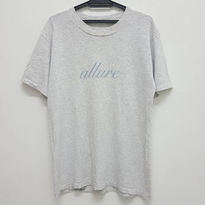 May include: A gray t-shirt with the word "allure" printed on the front in a light blue cursive font.