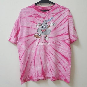 May include: Pink tie-dye t-shirt with a cartoon Hershey's Kiss character and the text "Hersheypark" in white.