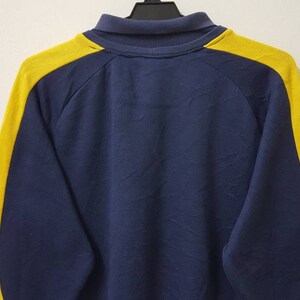 May include: A navy blue long-sleeved sweatshirt with yellow stripes down the sleeves.