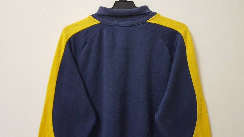 May include: A navy blue long-sleeved sweatshirt with yellow stripes down the sleeves.
