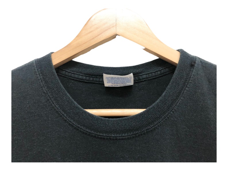 May include: Black t-shirt with a white tag that says "Hanes" on it. The shirt is on a wooden hanger.