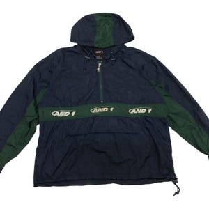 Könnte beinhalten: Eine marineblaue und grüne Kapuzenjacke mit Reißverschluss und einer Kängurutasche. Die Jacke trägt den Schriftzug "AND 1" auf der Vorderseite.