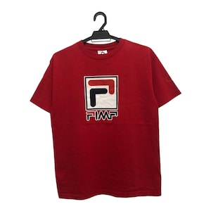 May include: A red short-sleeved t-shirt featuring a white, navy, and red logo with the word "PIMP" in white lettering. The t-shirt is displayed on a black hanger against a white backdrop. The logo is square-shaped.
