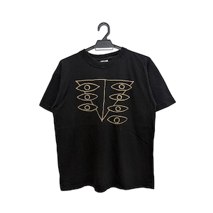 May include: Black t-shirt with a gold-colored eye design. The graphic features a series of stylized eyes arranged in a vertical pattern. The shirt is hanging on a black hanger against a white background.