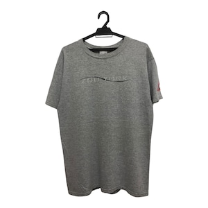 Puede incluir: Una camiseta gris jaspeada de manga corta, colgada de una percha negra. La camiseta presenta el texto "THE YORK" en un diseño curvo en el pecho. Un pequeño logotipo rojo es visible en la manga derecha.