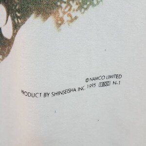 May include: White t-shirt with a green and white graphic print. The text "PRODUCT BY SHINSEISHA INC. 1995 (T800) N.1" and "&copy;NAMCO LIMITED" are printed on the bottom of the shirt.