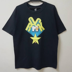 Puede incluir: Camiseta negra con un logotipo MTV amarillo, azul y blanco con la palabra "Rock" encima y "Music Television" debajo. Una estrella amarilla está debajo del logotipo.