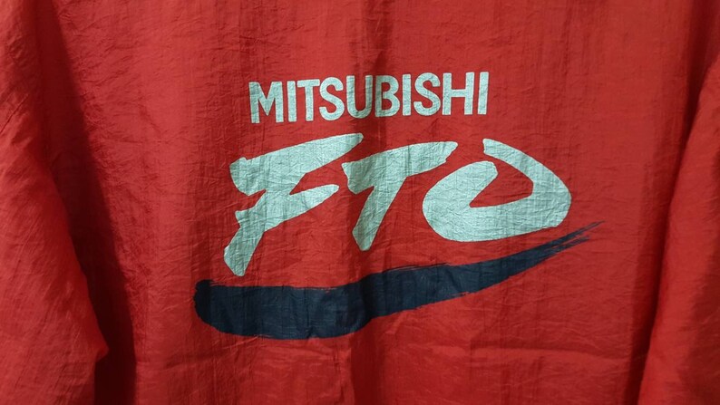 May include: Red jacket with a white and blue logo that says "MITSUBISHI ETO".