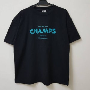 May include: Black t-shirt with a blue and white graphic that says "CHAMPS powered by MOTOROLA"