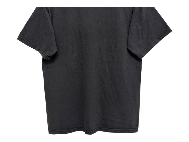 Puede incluir: Una camiseta gris carb&oacute;n con mangas cortas. La prenda tiene un aspecto ligeramente descolorido, lo que sugiere un estilo vintage o desgastado. La tela parece suave y c&oacute;moda, adecuada para ropa informal.