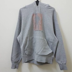 May include: A grey hooded sweatshirt with a graphic print of a building on the front. The print is in shades of pink, orange, and white.