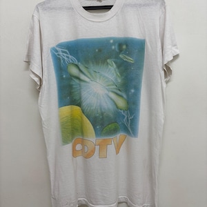 May include: White t-shirt with a colorful graphic design featuring a blue and green abstract image with the text "CDTV" in orange. The shirt is hanging on a black hanger.