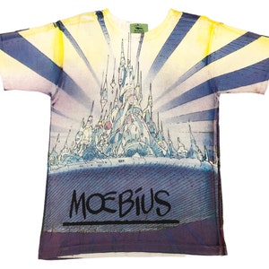 May include: A white t-shirt with a colorful graphic print of a futuristic city with a blue and yellow gradient background. The text "MOEBIUS" is printed in black at the bottom of the shirt.