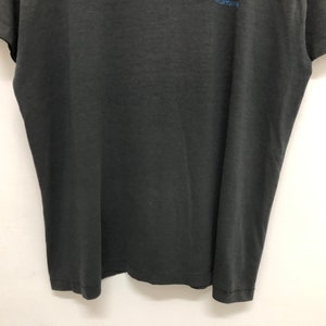May include: A black short-sleeved t-shirt with a faded blue graphic print on the front.