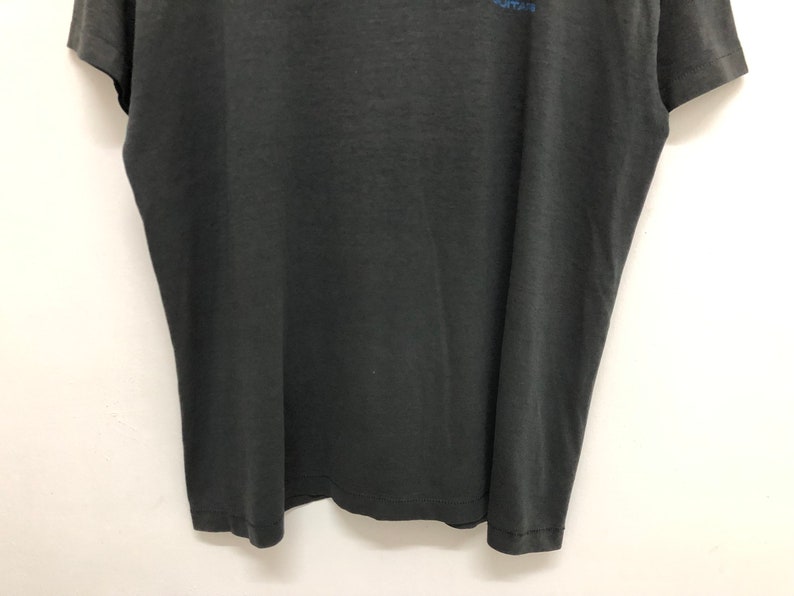 May include: A black short-sleeved t-shirt with a faded blue graphic print on the front.